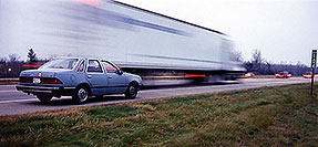 /images/133/1998-11-lancing-tempo-semi-pano.jpg - #00170: my blue 1986 Ford Tempo … them trucks go faaast … Nov 1998 -- Lancing, Michigan