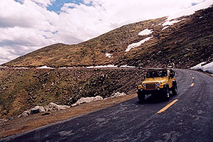 yellow Jeep Wrangler driving down from Mt Evans