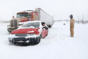 red Toyota and semi truck waiting for I-25 to open during a December snowstorm