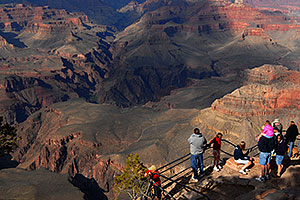 Girl in pink on dad`s shoulders and people enjoying views from Yavapai Point in Grand Canyon