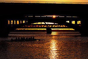 8 person sculling boat under Mill Road bridge at sunset at Tempe Town Lake
