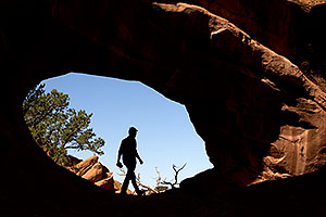 Hiker silhouette at Double O Arch in Arches National Park