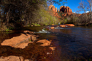 People jumping across rocks by Cathedral Rock and Oak Creek in Sedona