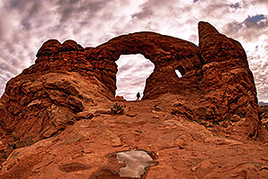 Hiker entering through Turret Arch in Arches National Park